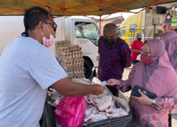 KHAIRUDIN Abu Hanipah (tengah) melihat orang ramai membeli ayam pada harga RM4 seekor pada program Kedai Bergerak Negeri Perak di Dataran Pekan Parit hari ini. - UTUSAN/MOHAMAD HAFIZI MOHD. SAID