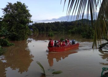 PASUKAN bomba menyelamatkan 11 sekeluarga yang terperangkap dalam banjir di Kampung Pantai, Sipitang hari ini. - IHSAN BOMBA