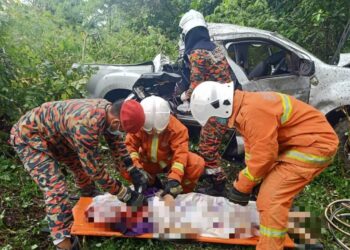 PASUKAN bomba mengeluarkan mangsa wanita yang maut dalam kemalangan di Kampung Paris, Kinabatangan hari ini. - IHSAN BOMBA