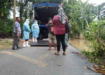 ANGGOTA Angkatan Pertahanan Awam Malaysia (APM) membantu memindahkan seorang pesakit Covid-19 bersama empat ahli keluarganya selepas kediaman yang terjejas banjir di Kampung Shukur di Dungun. - UTUSAN/NIK NUR IZZATUL HAZWANI NIK ADNAN