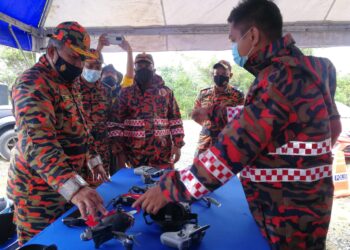 MD. Hilman Abd. Rashid (kiri) melihat dron yang digunakan bagi memantau situasi banjir di Terengganu. - UTUSAN/NIK NUR IZZATUL HAZWANI NIK ADNAN