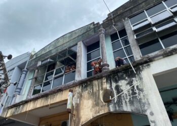 MOHD. Zairul Fahmi Mohd. Nazari (kiri) memujuk wanita yang dipercayai cuba terjun dari tingkat satu bangunan rumah kedai di Taman Bernam, Tanjung Malim. - UTUSAN/IHSAN JBPM PERAK