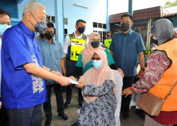 ISMAIL Sabri Yaakob menyampaikan bantuan banjir  kepada salah seorang mangsa banjir ketika meninjau PPS Balairaya Kampung Tandong di Buloh Kasap, Segamat. - UTUSAN/RAJA JAAFAR ALI