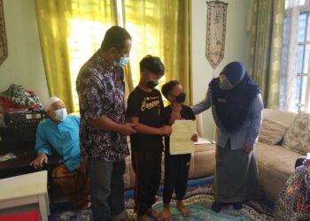 FARIHAH Che Husin selepas menyampaikan bantuan pencen penakat dan faedah pengurusan mayat kepada Ahmad Zamr Sulong di Kampung Gong Pak Maseh di Kuala Terengganu, hari ini.