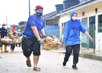 NORAINI Ahmad (berbaju biru) mengangkat sampah banjir di Temerloh, Pahang semalam dalam misi KPT bersama UiTM membantu mangsa banjir di sana.