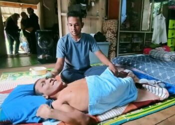 MUHAMMAD Hakimi Abdullah cekal menguruskan abangnya yang merupakan OKU di rumah mereka di Kampung Putat 7, Rantau Panjang, Kelantan. – UTUSAN/YATIMIN ABDULLAH