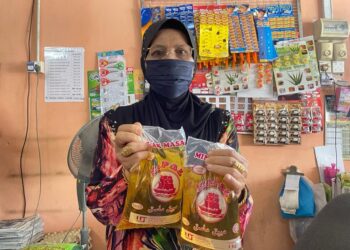 ZAWIYAH MAN menunjukkan minyak masak peket yang dijual di kedainya di Simpang Empat, Arau, Perlis, hari ini.- UTUSAN/NAZLINA NADZARI