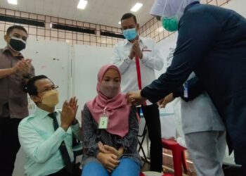 ZULKIFLI Abdullah (kiri) memberikan tepukan kepada Nur Sofiya Masturina Zainorden (duduk, kanan) yang menerima suntikan vaksin Covid-19 di PPV Dewan As-Syifa, Padang Matsirat, Langkawi hari ini. - UTUSAN/NUR AMALINA AZMAN