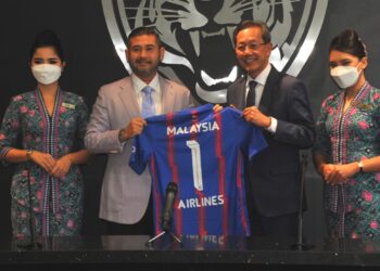 TUNKU Ismail Sultan Ibrahim menyampaikan jersi yang tertera nama Malaysia Airlines kepada Izham Ismail pada Majlis Menandatangani MoU antara JDT dan syarikat penerbangan itu di Ibu Pejabat Johor Darul Takzim, Iskandar Puteri. UTUSAN/RAJA JAAFAR ALI