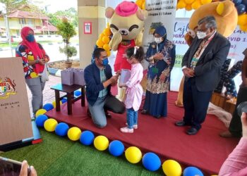 MUHAMAD Akmal Saleh memberikan gula-gula kepada kanak-kanak pada Program PICKids bersama ALP di Hospital Alor Gajah, Melaka. - UTUSAN/AMRAN MULUP