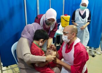 DR. Mohd. Zaqrul Razmal Mohd. Podzi memberikan suntikan vaksin Covid-19 kepada kanak-kanak pada Program PICKids di Pusat Perubatan Mawar di Seremban hari ini.-UTUSAN/NOR SHAFAWATI YUP.