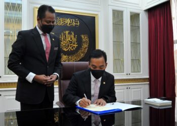 ONN Hafiz Ghazi menurunkan tandatangan memulakan tugas secara rasmi sambil diperhatikan Azmi Rohani di Pejabat Menteri Besar, Kota Iskandar di Iskandar Puteri. -  UTUSAN/RAJA JAAFAR ALI