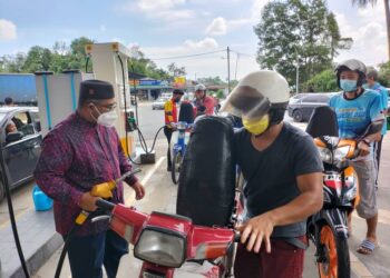 MOHD. Khairuddin Aman Razali (kiri) mengisi minyak motosikal secara percuma di stesen minyak di Padang Air, Kuala Nerus hari ini.