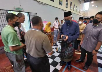 HAMZAH Zainudin menyampaikan sumbangan duit raya kepada orang ramai yang menghadiri Iftar Ala Madinah di Kompleks Sukan Komuniti Krubong, Melaka. - UTUSAN/AMRAN MULUP