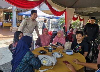 WAN Ahmad Fayhsal (kiri) berbual dengan tetamu yang menghadiri jamuan Hari Raya Aidilfitri di Kampung Tersusun Jalan Gula Simpang Ampat, Semanggol di Bagan Serai hari ini. - UTUSAN/WAT KAMAL ABAS