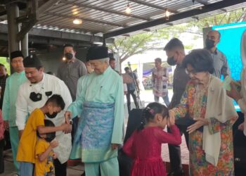 DR. Mahathir Mohamad (dua dari kiri) dan isterinya, Tun Siti Hasmah Mohd Ali (kanan) menyampaikan duit raya kepada kanak-kanak yang hadir pada Majlis Rumah Terbuka Aidilfitri Parlimen Langkawi di Dataran Telaga Walk, Langkawi, hari ini. - UTUSAN/NUR AMALINA AZMAN