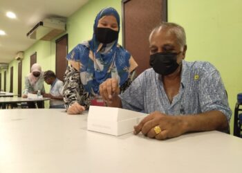 SEORANG petugas memberi tunjuk ajar menggunakan peranti kepada seorang pengundi warga emas di pusat pengundian PKR Cabang Hang Tuah Jaya di Bukit Baru, Melaka. - UTUSAN/MUHAMMAD SHAHIZAM TAZALI