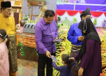 ABDUL RAHMAN Mohamad (tengah) menyampaikan duit raya kepada anak kakitangan Felcra Berhad dan tetamu sempena jamuan hari raya di Kuala Lipis di Lipis, Pahang. - UTUSAN/HARIS FADILAH AHMAD