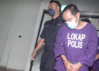 SUSPEK yang menikam leher ibu kandungnya sehingga maut diiring keluar anggota polis selepas dihadapkan ke Mahkamah Majistret Ayer Keroh, Melaka. - UTUSAN/RASUL AZLI SAMAD