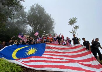 SEBAHAGIAN 50 orang peserta mengibarkan Jalur Gemilang besar ketika berada di puncak Bukit Panau setinggi 396 meter di Kampung Baharu di Jerantut, Pahang. - UTUSAN/HARIS FADILAH AHMAD