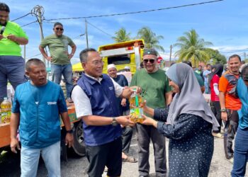 AWANG Hashim menyampaikan hadiah cabutan bertuah kepada pengunjung yang menghadiri Majlis Sukan Komuniti Banggol Besi di Tanah Merah, Pendang.