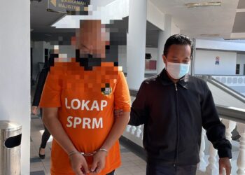 SUSPEK tiba di pekarangan Kompleks Mahkamah, Ayer Keroh, Melaka dengan memakai baju lokap SPRM dan diiringi pegawai penguatkuasa. - UTUSAN/MUHAMMAD SHAHIZAM TAZALI