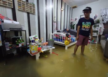 FAIZAL Zainudin melihat keadaan rumahnya di Juru, Pulau Pinang yang dinaiki air ekoran hujan lebat berterusan selama beberapa jam bermula petang semalam hingga tengah malam tadi. - Pix IQBAL HAMDAN