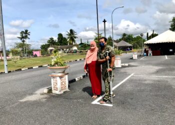 MOHAMAD Akmal Zaini bertongkat bersama isterinya yang datang mengundi awal di Kem Desa Pahlawan Kok Lanas, Kota Bharu, Kelantan, hari ini. - UTUSAN/ ROSLIZA MOHAMED