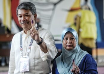 MOHAMAD Hasan dan isteri, Datin Seri Raja Salbiah Tengku Nujumudin menunjukkan jari yang telah dicelup dakwat di pusat mengundi SRJK Cina Chung Hua, Rantau, Seremban hari ini. - UTUSAN/MOHD. SHAHJEHAN MAAMIN