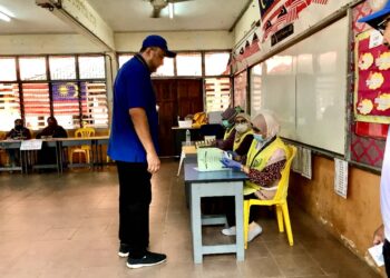 ROSMADI Ismail (berdiri) untuk membuat semakan nama sebelum membuang undi di SK Sri Bemban, Kota Bharu, Kelantan hari ini.-UTUSAN/ ROSLIZA MOHAMED