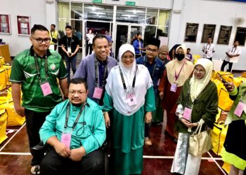 MUMTAZ Md. Nawi (tengah) bersama suami, Mohd. Sukiman Yasin (berkerusi roda) di Pusat Penjumlahan Undi Rasmi di SMK Dato Biji Wangsa, Tumpat, Kelantan. - UTUSAN/ ROSLIZA MOHAMED