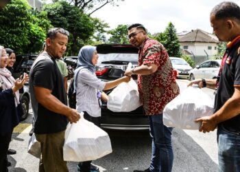 WAKIL Ahmad Faizal menghantar nasi beriani kepada petugas media yang menunggu di Jalan Setia Bakti 2, di sini. - UTUSAN/AFIQ RAZALI