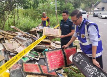 KETUA Unit Operasi Bahagian Penguatkuasaan JHEAINS, Ahmad Zaki Hamzah (kanan) menunjukkan longgokan perhiasan ayat suci al-Quran yang ditemui di kawasan tempat pembuangan sampah haram di Jalan P/AM 2 Kawasan Perindustrian Arab Malaysia, Nilai, Seremban, semalam.-UTUSAN/NOR SHAFAWATI YUP.