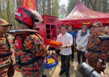 NGA Kor Ming (tengah) menyerahkan peralatan sebagai gimik pelancaran Majlis Keselamatan Aktiviti di Air (MKAA) Peringkat negeri Kelantan di Pantai Senok, Bachok, Kelantan hari ini.-UTUSAN/TOREK SULONG