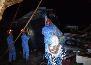 ANGGOTA APM Daerah Yan memantau rumah penduduk yang rosak diterbangkan angin kencang di Kampung Tualang, Bukit Besar di Yan. -IHSAN APM