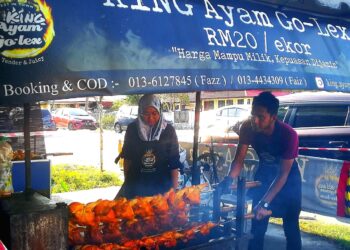 KHAIRUL Faiz Abas (kanan) memanggang ayam golek di gerainya di Kampung Sungai Udang, Klang, Selangor. - UTUSAN/ABDUL RAZAK IDRIS