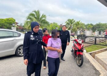 TERTUDUH Sherly Gutterrez (dua kiri) dan Aliuddin Abdul Aziz (belakang) diiringi oleh anggota polis ke Mahkamah Sesyen Gua Musang, Kelantan. - UTUSAN/AIMUNI TUAN LAH