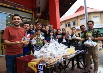 MURTADHATUMIZI Mustapha (kiri) bersama kakitanganya menunjukkan kuih akok yang diagihkan kepada penduduk di sekitar Kota Bharu, Kelantan semalam.-UTUSAN/KAMARUL BISMI KAMARUZAMAN