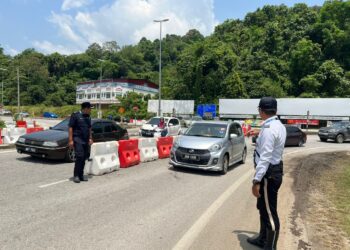 ANGGOTA polis trafik memantau keadaan lalu lintas bagi memastikan ia bergerak lancar di laluan alternatif Jalan Gua Musang-Kuala Lipis di hadapan Ibu Pejabat Polis Daerah (IPD) Gua Musang, Kelantan hari ini.UTUSAN/AIMUNI TUAN LAH