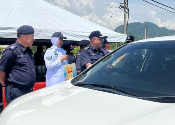 MAT Kasim Karim (kanan) menyampaikan bungkusan kuih raya kepada perantau yang melalui jalan alternatif Jalan Gua Musang-Kuala Lipis di Kampung Tanah Putih, Gua Musang, Kelantan  hari ini.UTUSAN/AIMUNI TUAN LAH