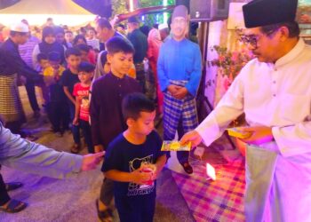 MD. Alwi Che Ahmad (kanan) memberikan sumbangan duit raya kepada kanak-kanak yang hadir ke Majlis Rumah Terbuka Aidilfitri DUN Kok Lanas di Kampung Upeh, Ketereh, Kelantan malam tadi-UTUSAN/YATIMIN ABDULLAH