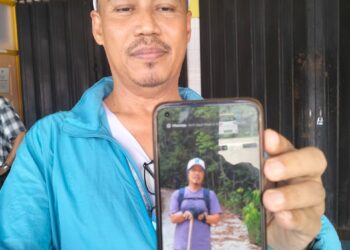 HUSIN Sulaiman menunjukkan gambar kembarnya, Hasan yang meninggal dunia semasa mendaki Bukit Panau, Tanah Merah ketika ditemui di Hospital Pasir Mas, Kelantan hari ini-UTUSAN/ROHANA ISMAIL