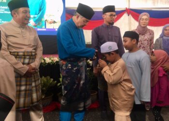 AHMAD Zahid Hamidi (dua kiri) menyampaikan sumbangan duit raya kepada kanak-kanak yang menghadiri Majlis Mesra Aidilfitri di Perkarangan Maahad Tahfiz Yaakubiah, Machang, Kelantan hari ini-UTUSAN/ROSMIZAN RESDI