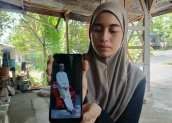 SITI Rajwa Ismi menunjukkan gambar abangnya yang maut dalam kemalangan di Kampung Batang Merbau, Tanah Merah. - UTUSAN/ROHANA MOHD. NAWI