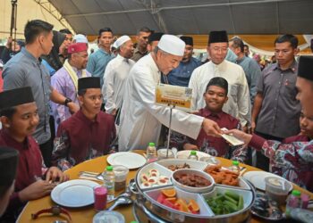 AHMAD Zahid Hamidi (tengah) menyampaikan sumbangan duit raya  kepada anak-anak yatim yang hadir pada Majlis Santunan Kasih Ramadan di Masjid Al-Ansar, Kem Seri Pantai, Seberang Takir, Kuala Nerus, malam ini. - UTUSAN/PUQTRA HAIRRY ROSLI