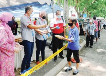 ZAITON Ismail (kiri) melihat pembahagian makanan kepada gelandangan ketika meninjau golongan itu di tempat letak kereta Jalan Ibrahim, Johor Bahru semalam. – FOTO/RAJA JAAFAR ALI