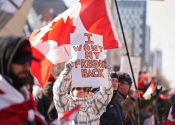 SEORANG wanita memegang sepanduk semasa protes Covid-19 di Toronto. - AFP