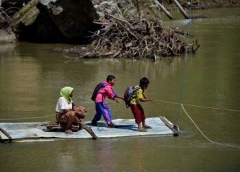 BEBERAPA pelajar menarik tali untuk menyeberangi sungai menggunakan rakit di Siron, Aceh, Indonesia. - AFP