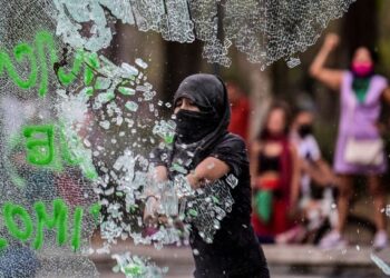 SEORANG penunjuk perasaan memecahkan pintu masuk stesen tren Hidalgo di Mexico City, Mexico. - AFP