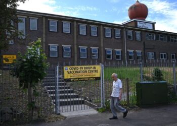 SEORANG pejalan kaki melintasi Masjid e Saliheen yang dijadikan sebagai pusat pemberian vaksin di Blackburn, barat laut England. - AFP